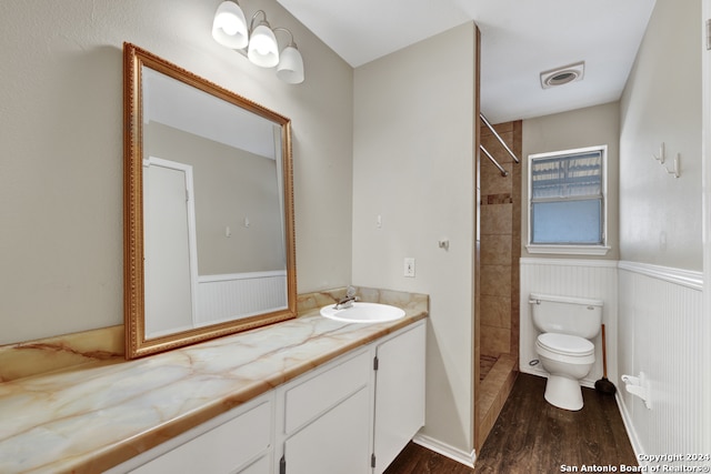 bathroom with vanity, hardwood / wood-style floors, toilet, and tiled shower