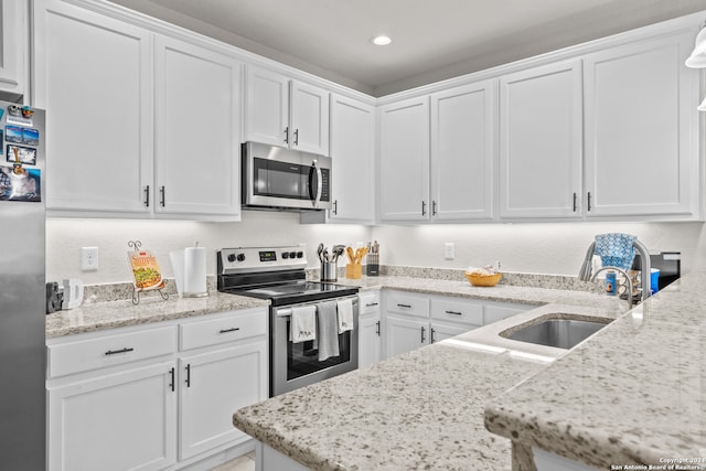 kitchen featuring light stone countertops, white cabinetry, sink, and stainless steel appliances