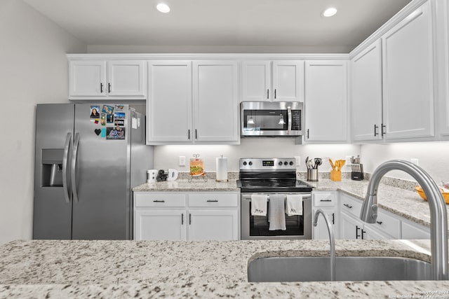 kitchen with white cabinetry, sink, stainless steel appliances, and light stone counters