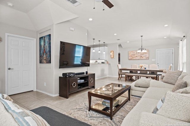 tiled living room with ceiling fan with notable chandelier and vaulted ceiling