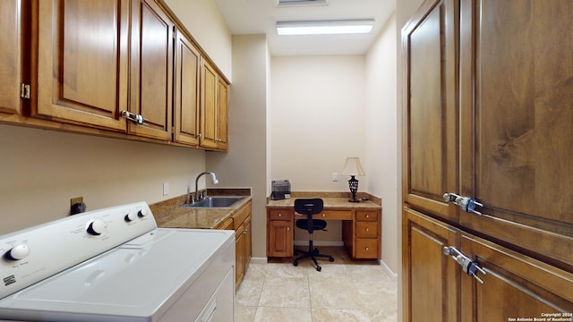 laundry room featuring light tile patterned flooring, cabinets, sink, and washer / dryer