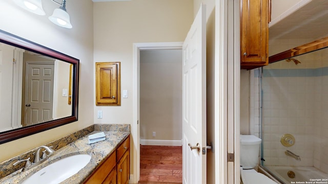 full bathroom featuring wood-type flooring, tiled shower / bath, vanity, and toilet