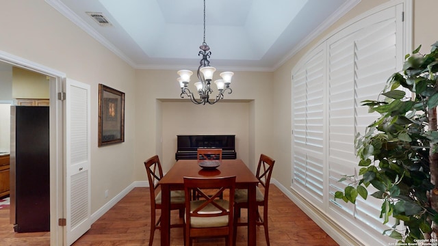 dining space with ornamental molding, a raised ceiling, a chandelier, and dark wood-type flooring