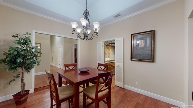 dining area featuring a notable chandelier, hardwood / wood-style floors, and crown molding