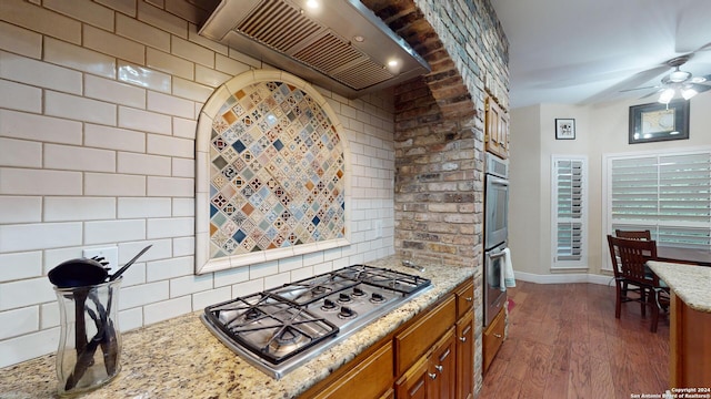 kitchen with appliances with stainless steel finishes, light stone counters, ceiling fan, premium range hood, and dark hardwood / wood-style floors