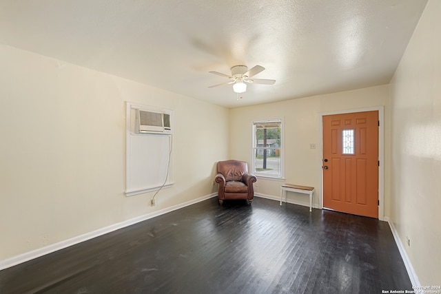 foyer entrance featuring ceiling fan, a textured ceiling, dark wood-type flooring, and a wall unit AC