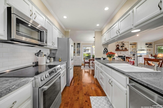 kitchen featuring appliances with stainless steel finishes, ornamental molding, white cabinetry, and dark hardwood / wood-style floors