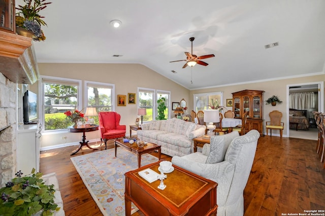 living room featuring ceiling fan, lofted ceiling, a stone fireplace, dark wood-type flooring, and crown molding