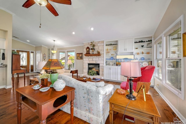 living room with ornamental molding, lofted ceiling, dark wood-type flooring, and a stone fireplace