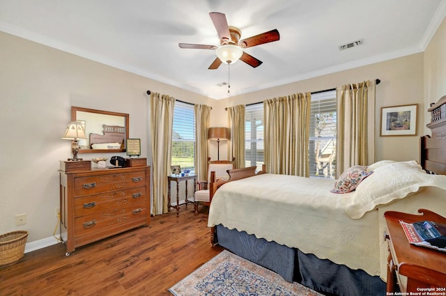 bedroom featuring multiple windows, dark hardwood / wood-style floors, ceiling fan, and crown molding