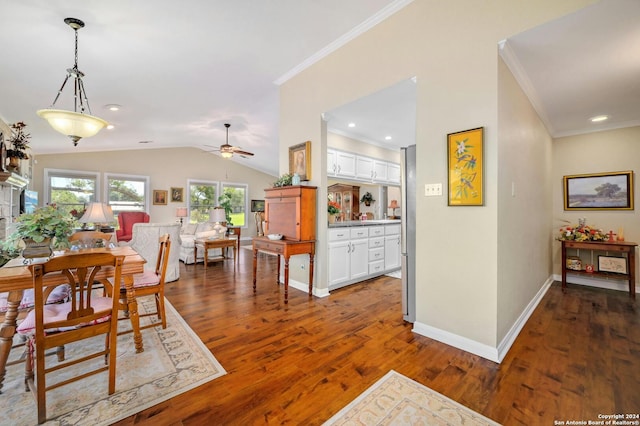 dining space with ceiling fan, dark hardwood / wood-style floors, vaulted ceiling, and crown molding