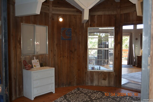 entryway with beam ceiling, wooden walls, hardwood / wood-style floors, and ceiling fan