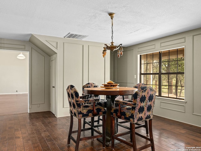 dining area with a textured ceiling and dark hardwood / wood-style floors