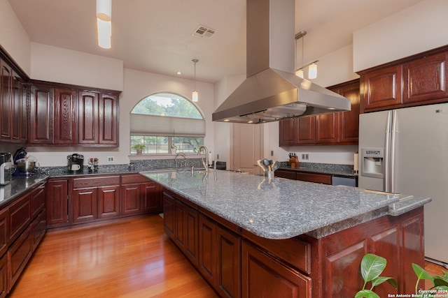 kitchen featuring island exhaust hood, hanging light fixtures, stainless steel fridge with ice dispenser, a kitchen island with sink, and light hardwood / wood-style floors