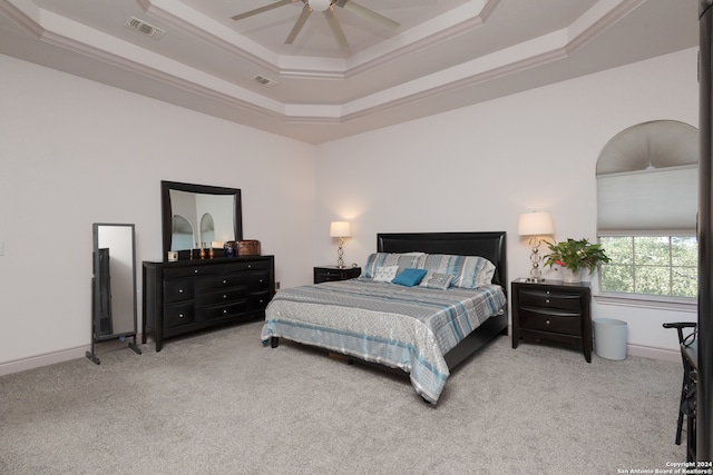 bedroom with ornamental molding, light colored carpet, a raised ceiling, and ceiling fan