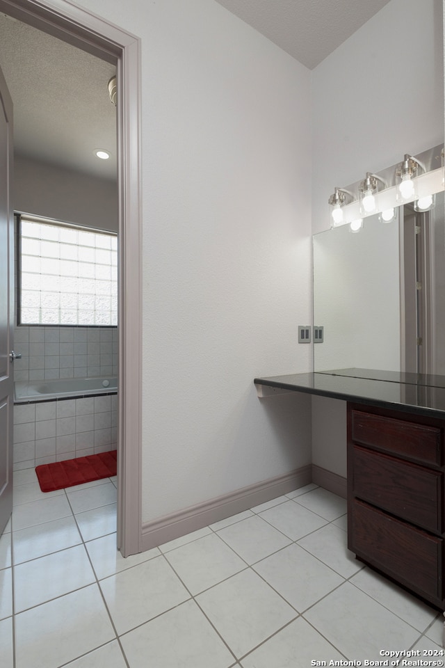 bathroom with vanity, a bathtub, a textured ceiling, and tile patterned floors