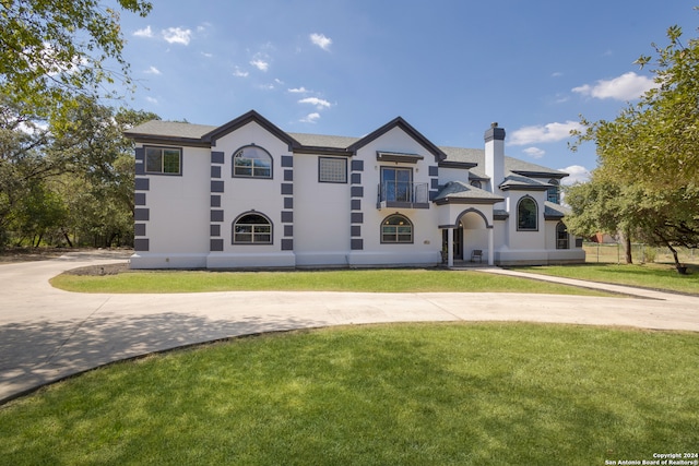 view of front of house with a balcony and a front lawn