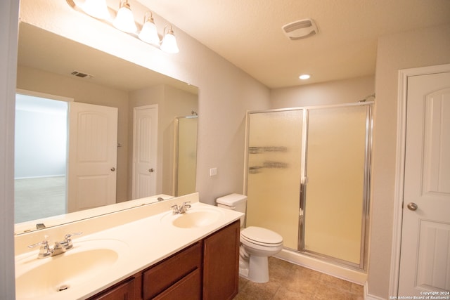 bathroom with vanity, a shower with shower door, toilet, and tile patterned flooring