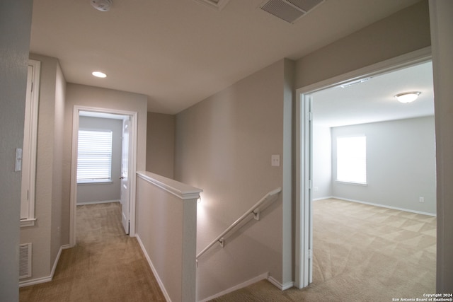 corridor featuring light colored carpet and plenty of natural light