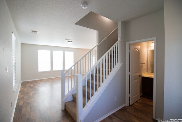 staircase featuring a textured ceiling and hardwood / wood-style flooring