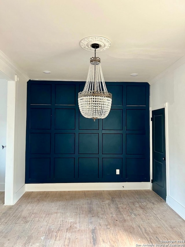 unfurnished room with light hardwood / wood-style flooring, an inviting chandelier, and crown molding