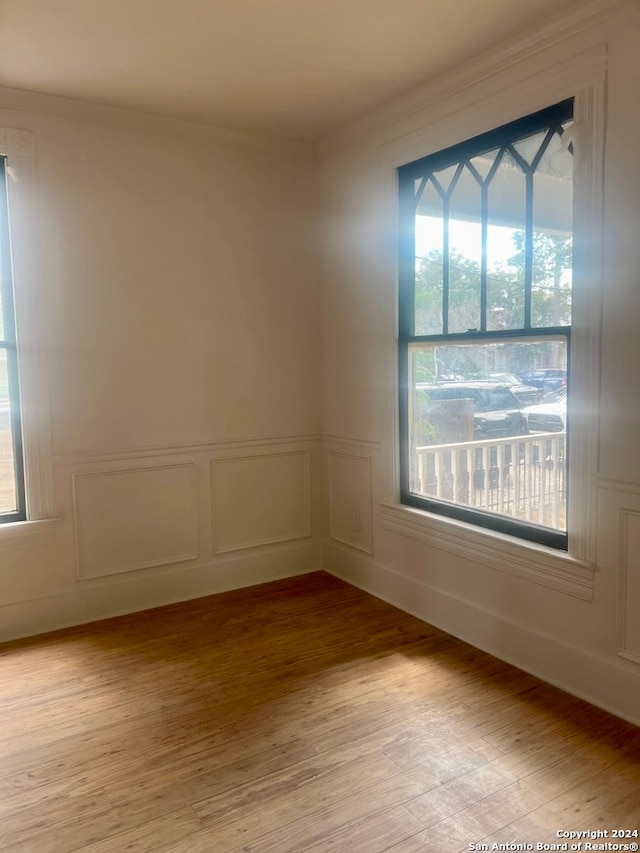 spare room with light wood-type flooring and crown molding