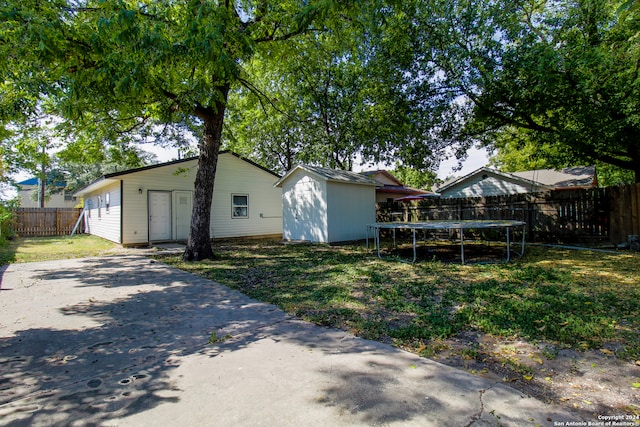 back of house featuring a trampoline and a yard