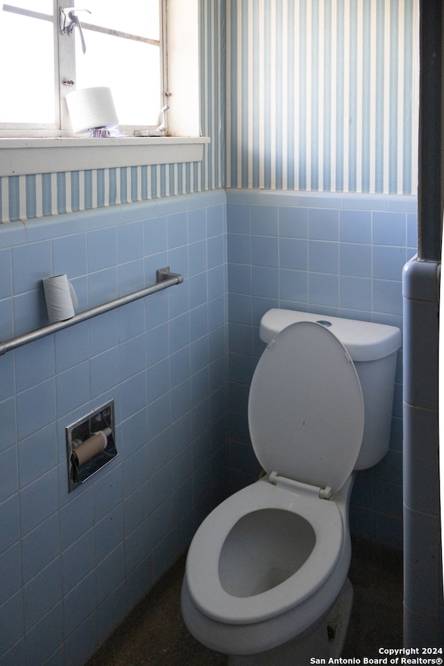 bathroom with tile walls and toilet