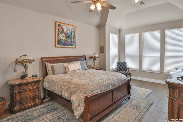 bedroom featuring wood-type flooring, a tray ceiling, vaulted ceiling, and ceiling fan