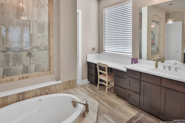 bathroom featuring vanity, separate shower and tub, and an inviting chandelier