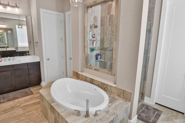 bathroom featuring a notable chandelier, plus walk in shower, and vanity