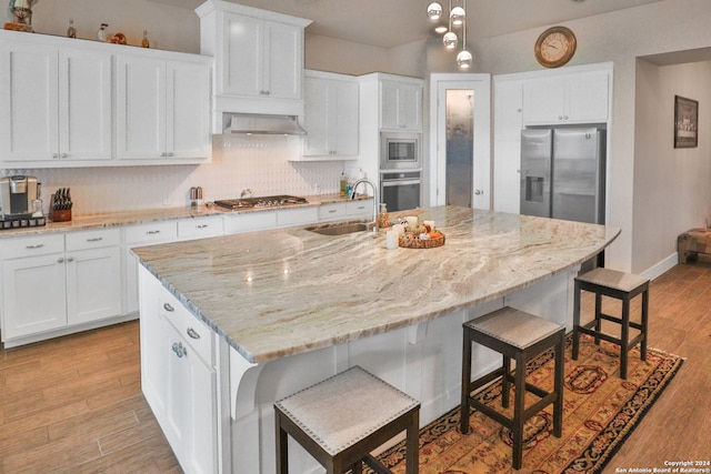 kitchen featuring white cabinets, appliances with stainless steel finishes, a center island with sink, and sink