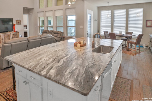 kitchen featuring white cabinetry, pendant lighting, a kitchen island with sink, and sink