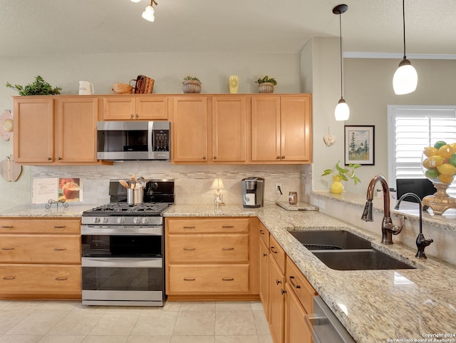 kitchen with light brown cabinetry, stainless steel appliances, hanging light fixtures, and sink