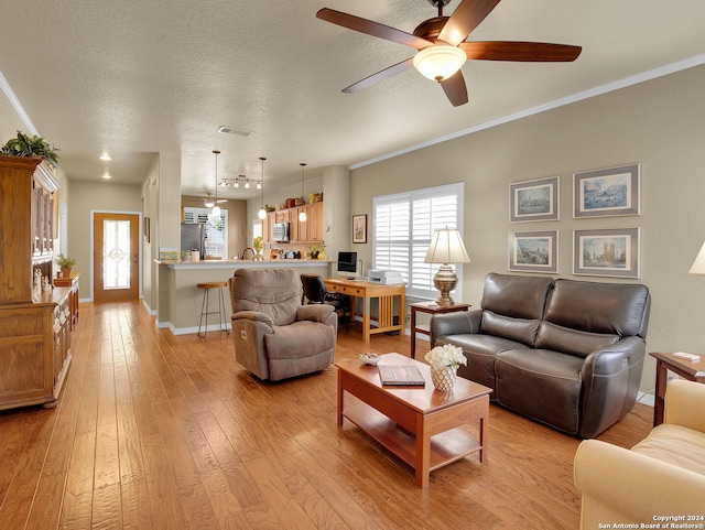 living room with a textured ceiling, crown molding, ceiling fan, and light hardwood / wood-style flooring