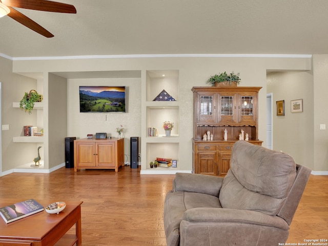 living room with light wood-type flooring, ceiling fan, crown molding, and built in features