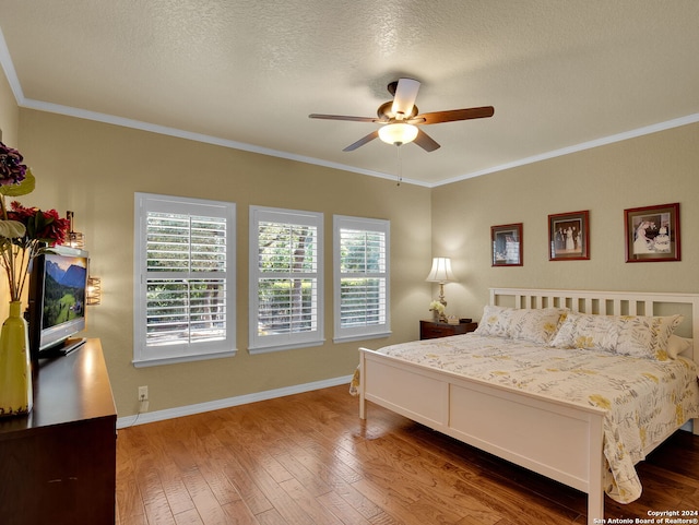 bedroom with a textured ceiling, wood-type flooring, ornamental molding, and ceiling fan