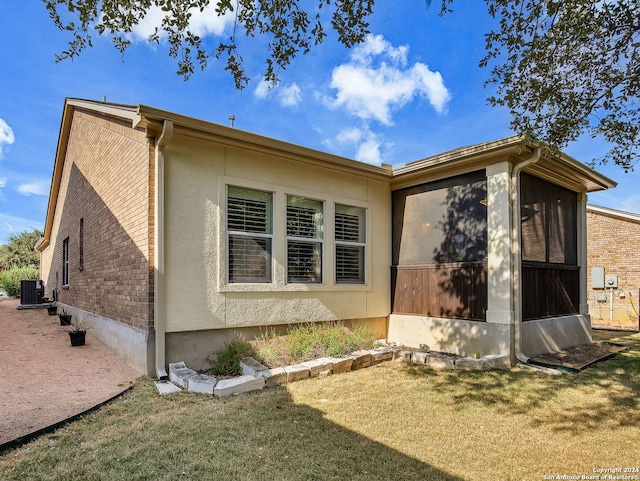 view of home's exterior featuring a lawn, a sunroom, and central AC