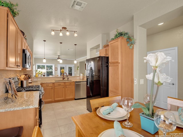 kitchen featuring ceiling fan, light stone counters, sink, kitchen peninsula, and appliances with stainless steel finishes