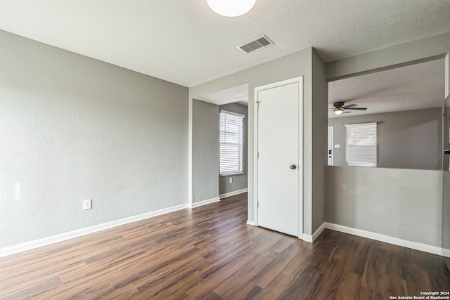 empty room with ceiling fan, a textured ceiling, and dark hardwood / wood-style floors