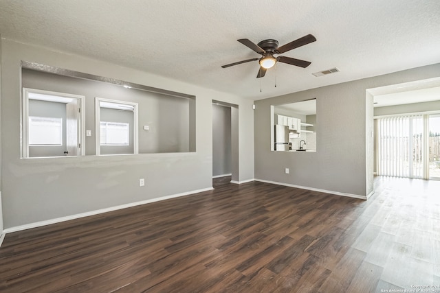 empty room featuring ceiling fan, a textured ceiling, sink, and dark wood-type flooring