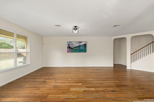 spare room featuring wood-type flooring and a textured ceiling