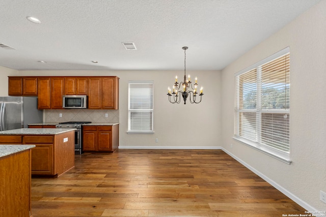 kitchen featuring decorative backsplash, dark wood-type flooring, a notable chandelier, hanging light fixtures, and appliances with stainless steel finishes