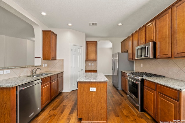 kitchen featuring stainless steel appliances, dark hardwood / wood-style flooring, a center island, and light stone counters