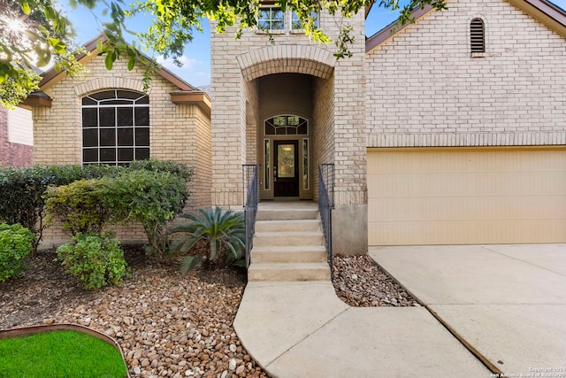 property entrance featuring a garage, driveway, and brick siding