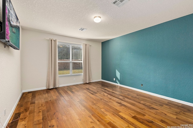 unfurnished room featuring hardwood / wood-style flooring and a textured ceiling