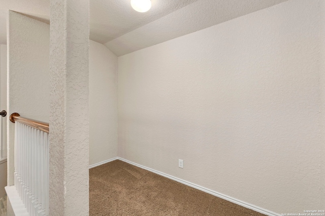 carpeted spare room with vaulted ceiling and a textured ceiling