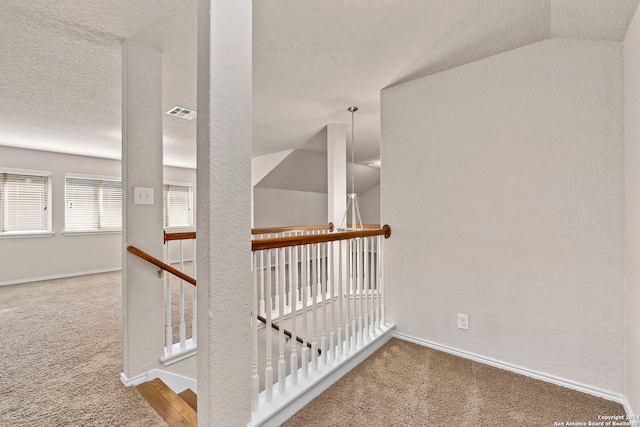 stairs with lofted ceiling, carpet floors, and a textured ceiling