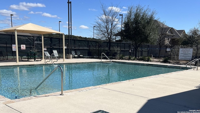 pool with a patio area and fence