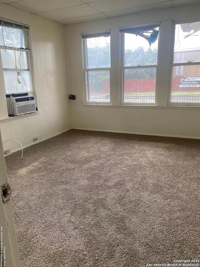 carpeted spare room with a paneled ceiling, cooling unit, and plenty of natural light